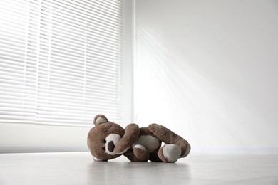 Photo of Cute lonely teddy bear on floor in empty room