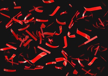 Shiny red confetti falling down on black background