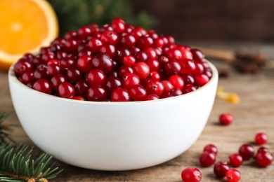 Fresh ripe cranberries and fir branch on wooden table, closeup
