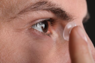 Closeup view of man putting contact lens in his eye