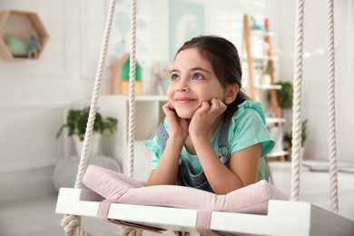 Photo of Cute little girl playing on swing at home