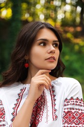 Photo of Beautiful woman in embroidered shirt outdoors. Ukrainian national clothes