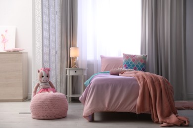 Photo of Bed with beautiful linens in children's room. Modern interior design