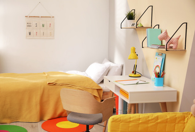 Stylish child room interior with comfortable bed and desk