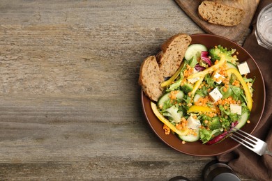 Delicious salad with lentils, vegetables and bread served on wooden table, flat lay. Space for text