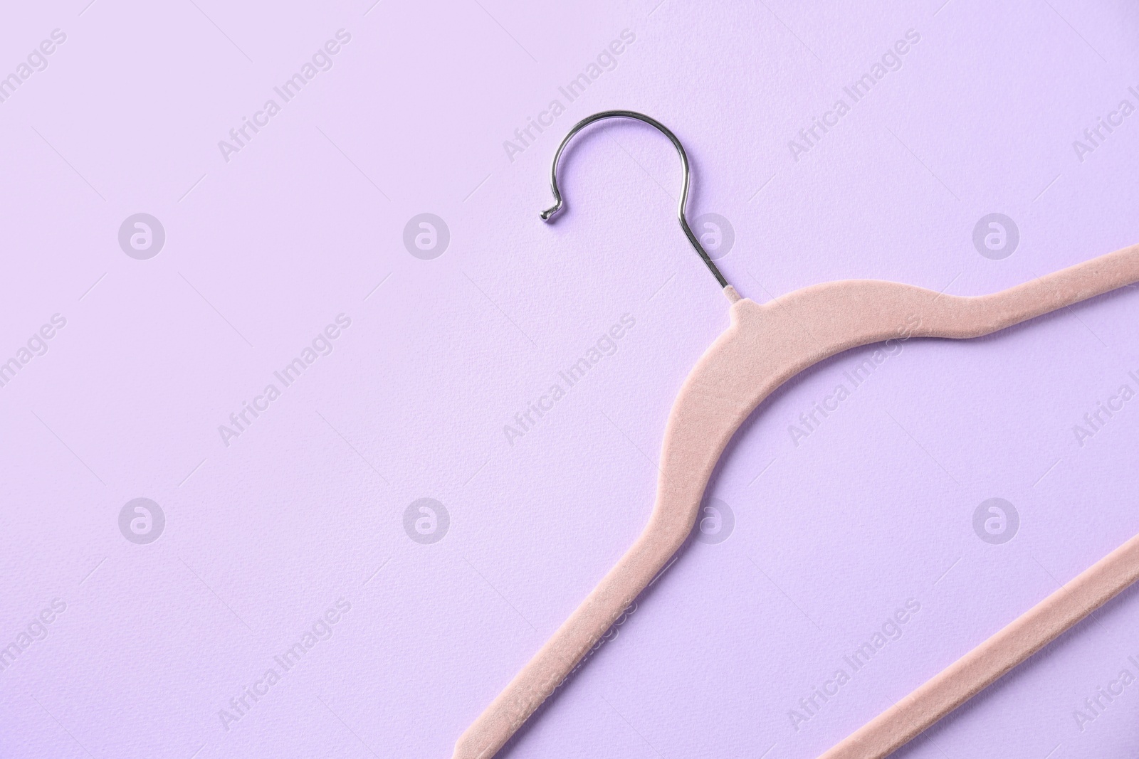 Photo of One beige hanger on violet background, top view. Space for text