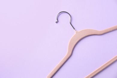 One beige hanger on violet background, top view. Space for text