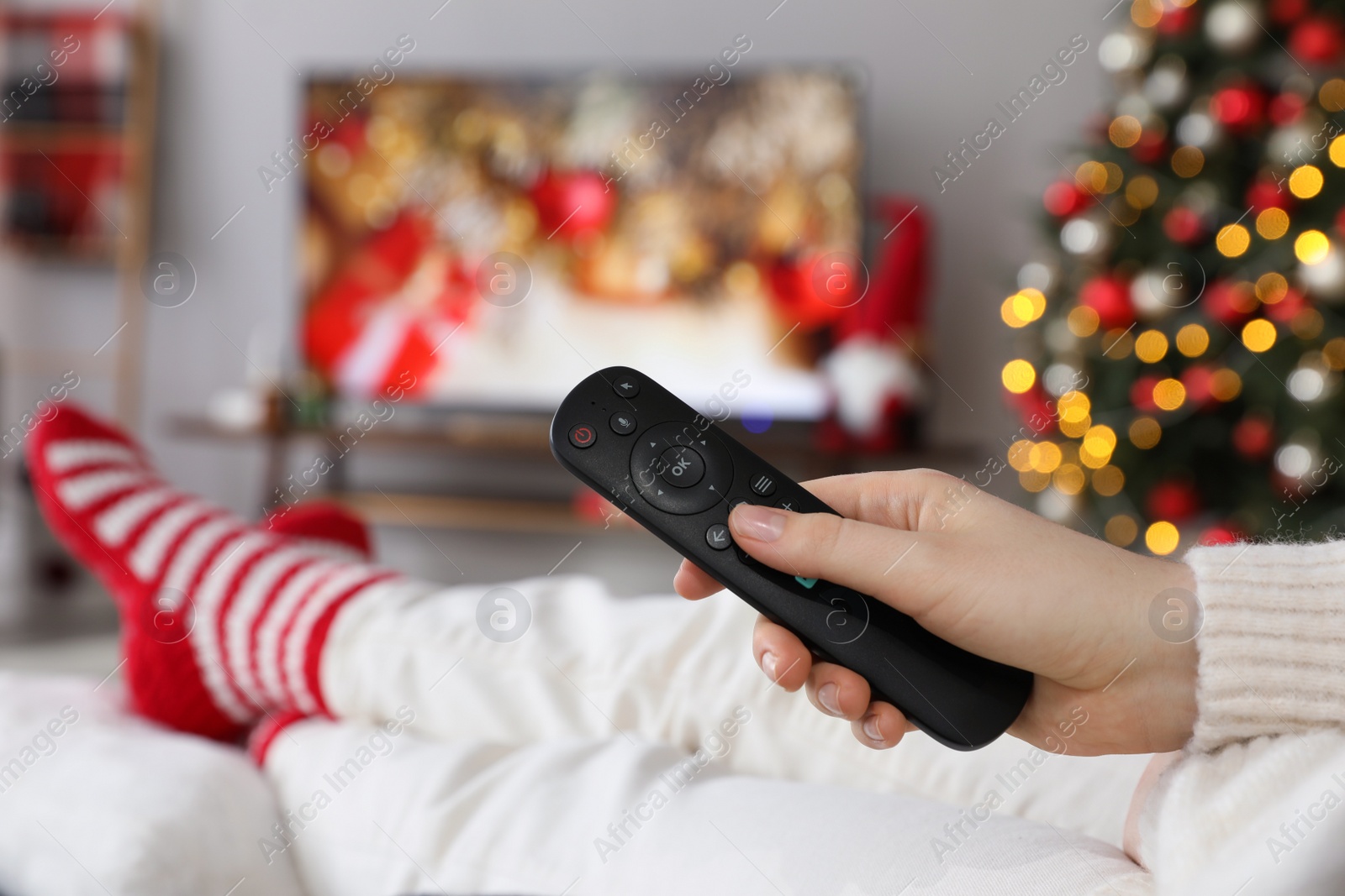 Photo of Woman with remote control watching TV at home, closeup