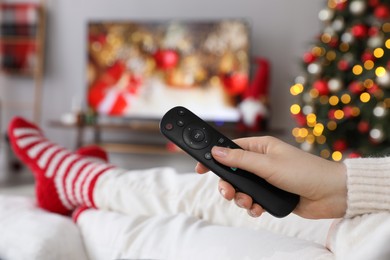 Photo of Woman with remote control watching TV at home, closeup