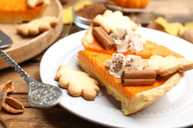 Photo of Slices of delicious homemade pumpkin pie on wooden table, closeup