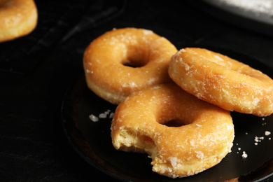 Photo of Sweet delicious glazed donuts on black table