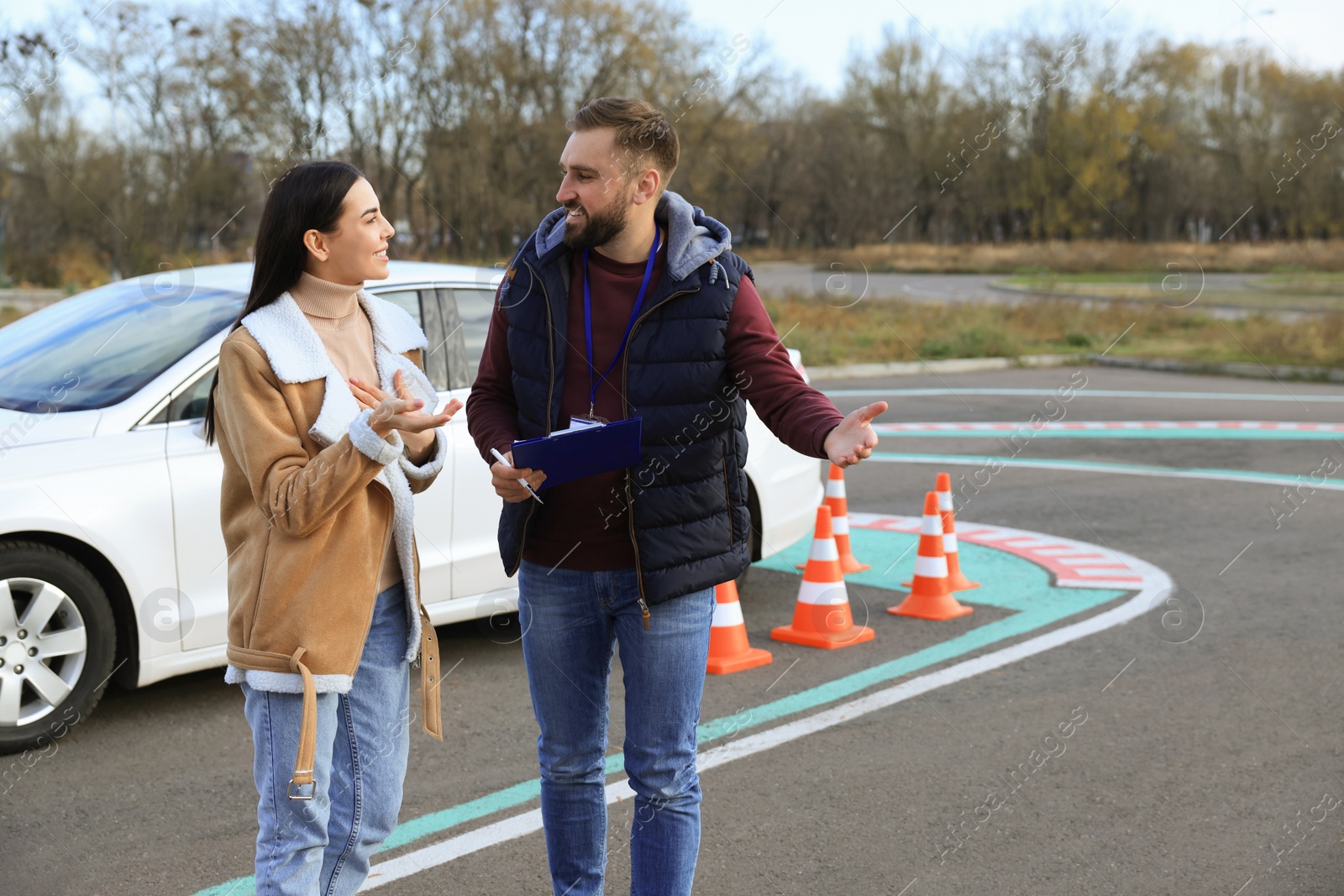 Photo of Young woman with instructor near car at driving school test track