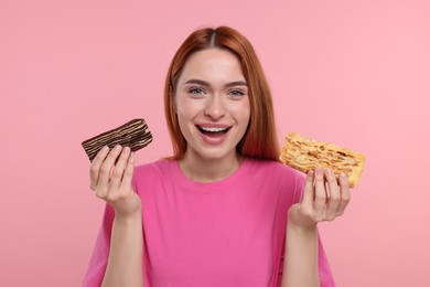 Young woman with pieces of tasty cake on pink background