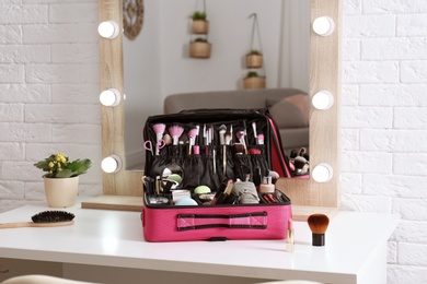 Beautician case with professional makeup products and tools on dressing table