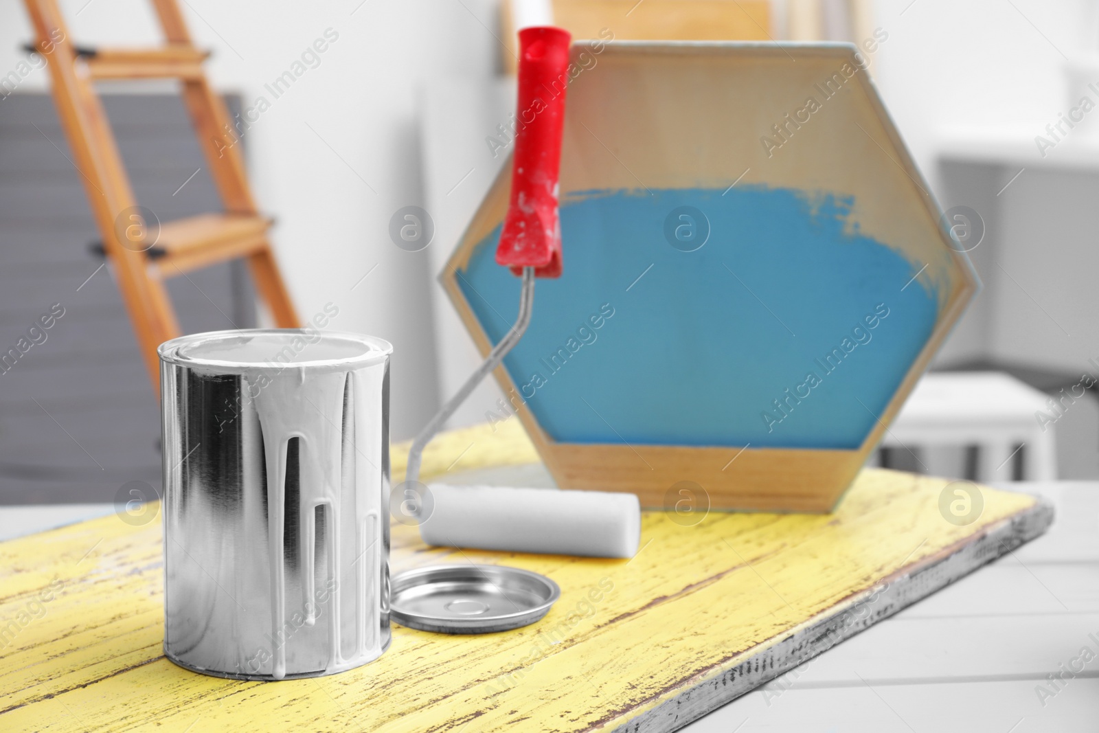 Photo of Can of paint and roller on blue wooden table indoors, space for text