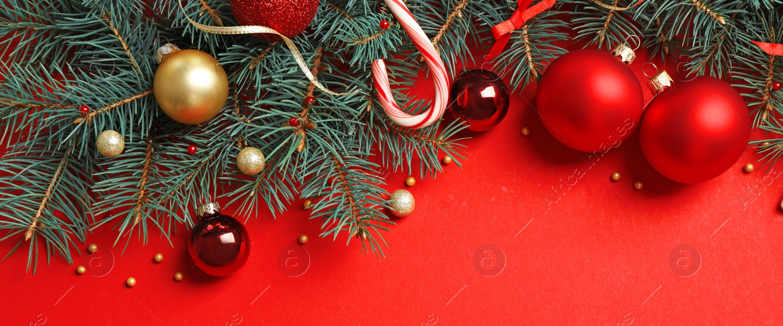 Photo of Fir tree branches with Christmas decoration on red background, flat lay. Space for text