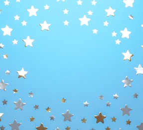 Frame made of confetti stars with space for text on blue background, top view. Christmas celebration