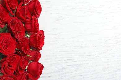 Beautiful red rose flowers on wooden background, top view