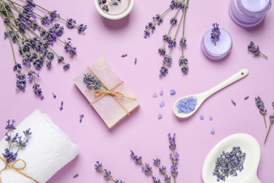 Photo of Cosmetic products and lavender flowers on lilac background, flat lay