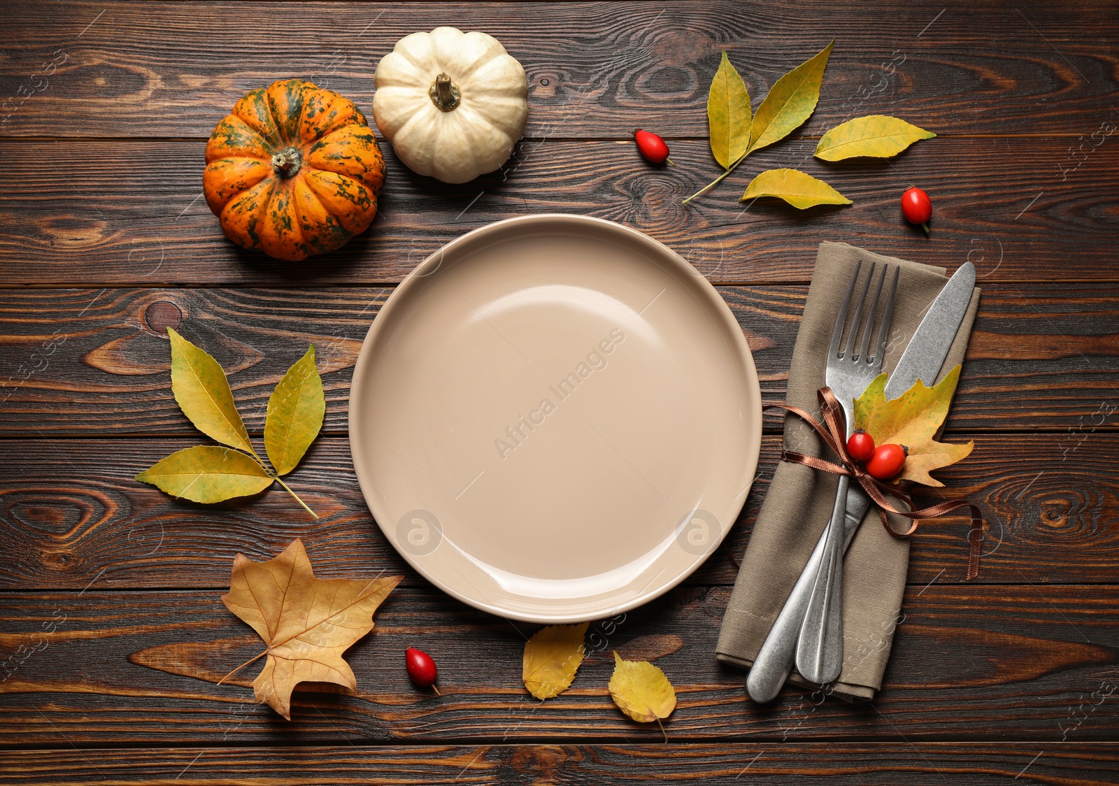 Photo of Festive table setting with autumn leaves and pumpkins on wooden background, flat lay. Thanksgiving Day celebration