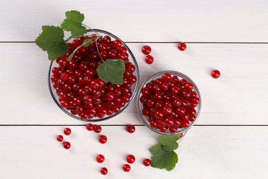 Many ripe red currants and leaves on white wooden table, flat lay