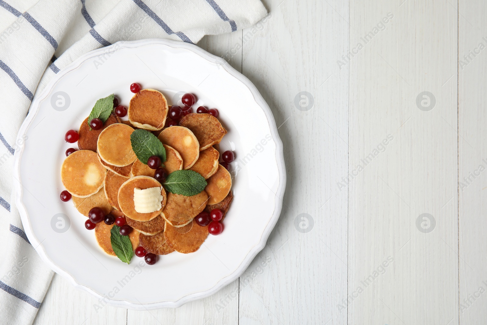 Photo of Cereal pancakes with cranberries and butter on white wooden table, flat lay. Space for text