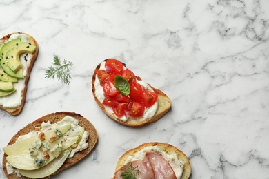 Photo of Different tasty bruschettas and space for text on marble background, flat lay