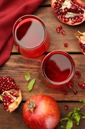 Photo of Tasty pomegranate juice in glasses and fresh fruits on wooden table, flat lay