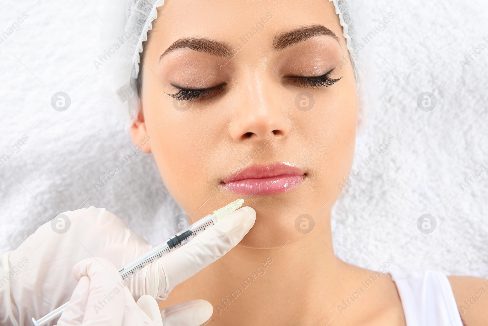 Photo of Young woman getting lip injection in beautician salon, closeup