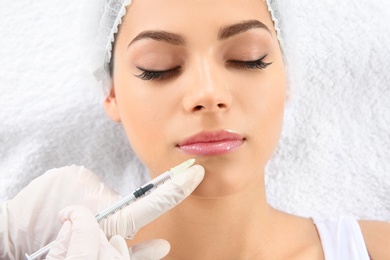 Photo of Young woman getting lip injection in beautician salon, closeup