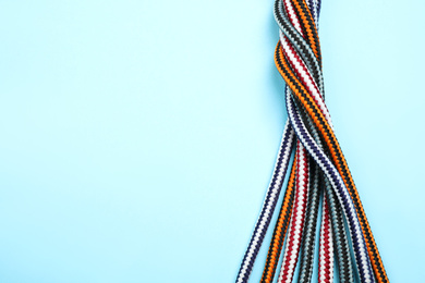 Photo of Top view of twisted colorful ropes on light blue background, space for text. Unity concept