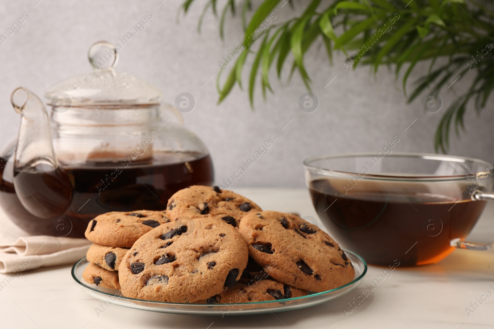 Photo of Delicious chocolate chip cookies and tea on white marble table