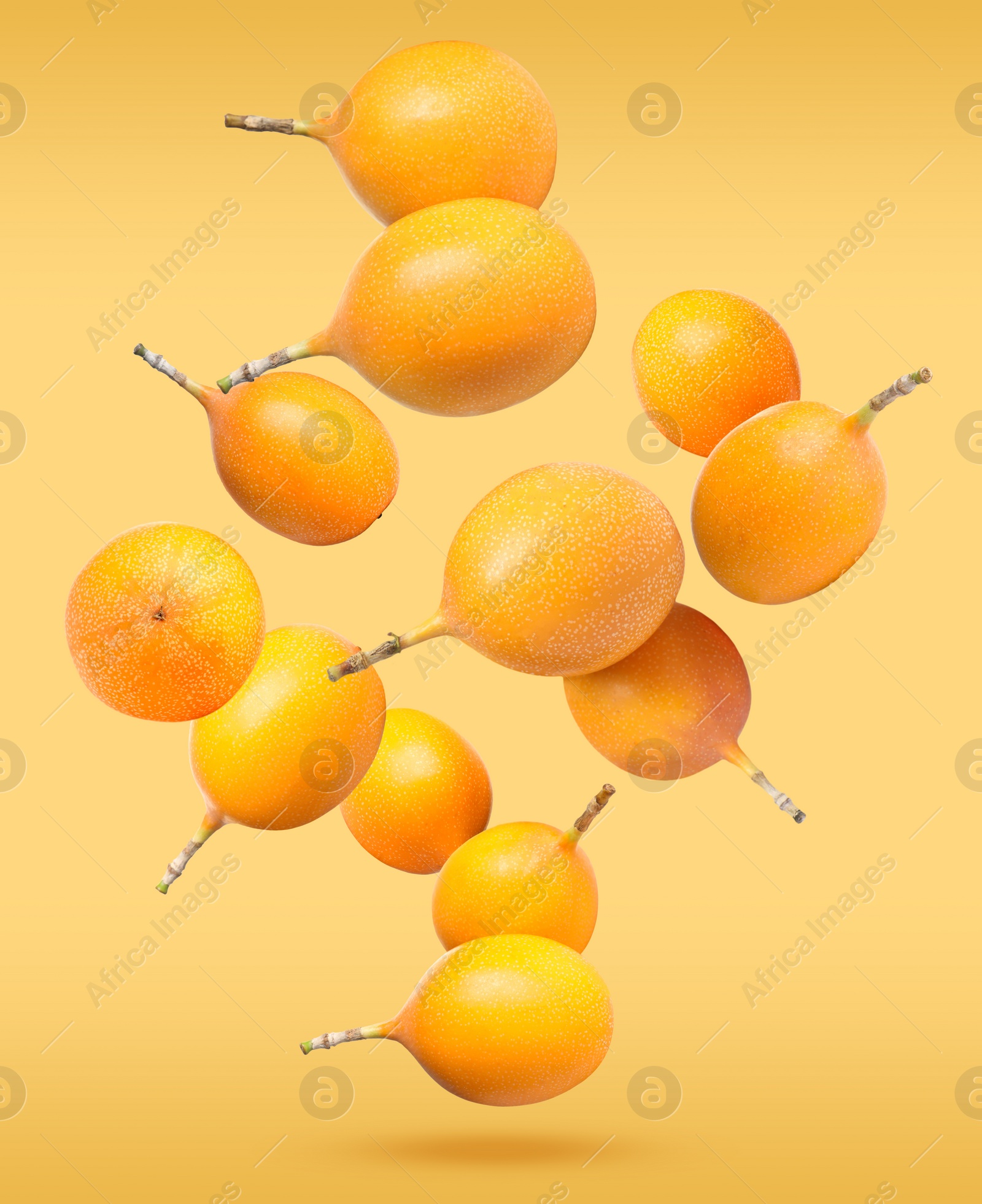 Image of Delicious ripe granadillas falling on orange background