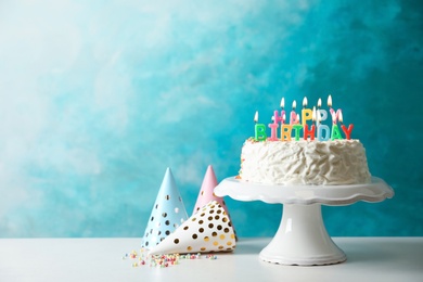 Photo of Birthday cake with candles on table against color background