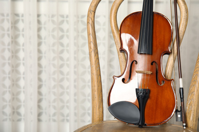 Photo of Classic violin and bow on chair indoors. Space for text