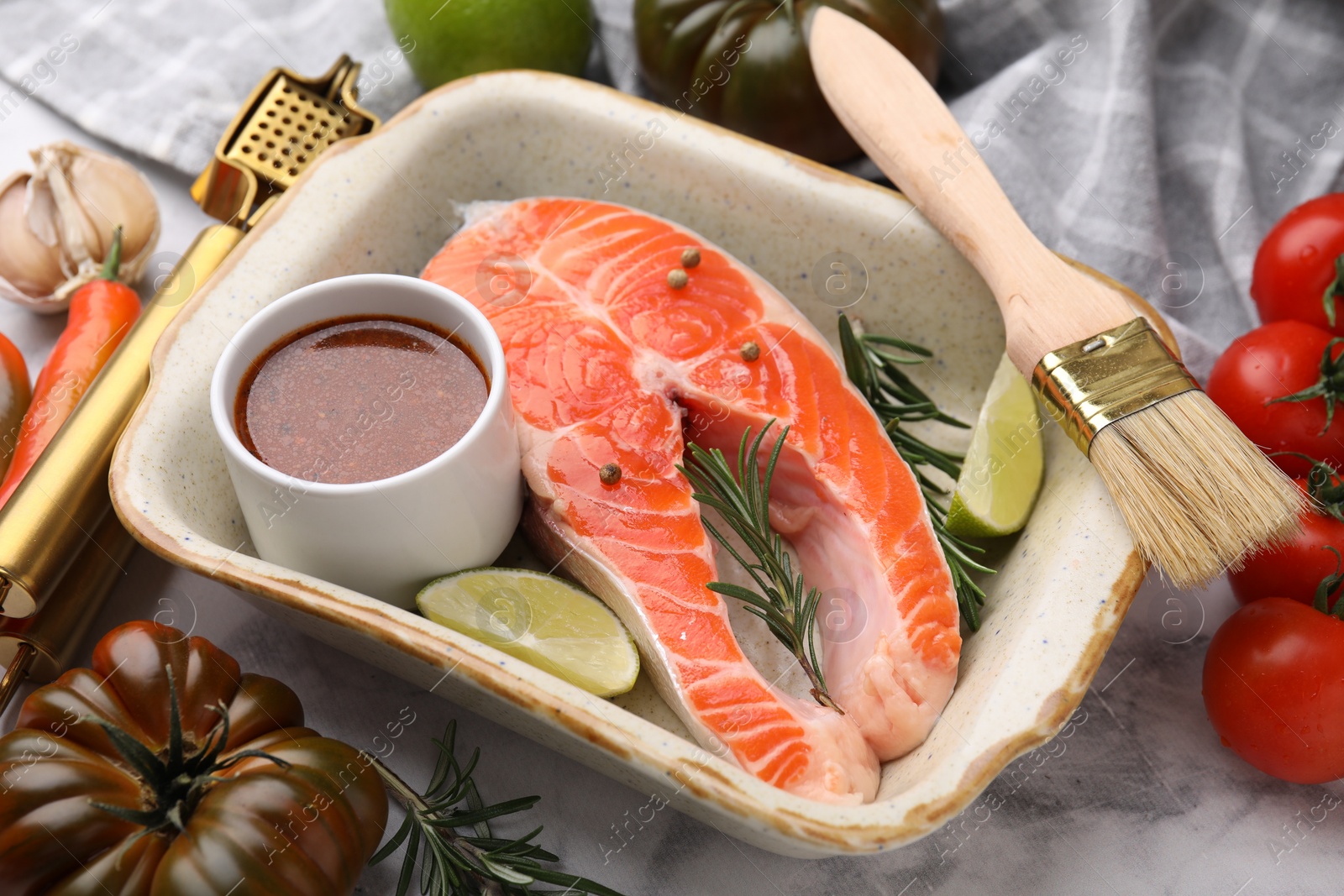 Photo of Fresh fish, lime, rosemary, marinade in baking dish and other products on table, closeup