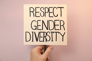 Photo of Woman holding sign with text Respect Gender Diversity on pink background, closeup
