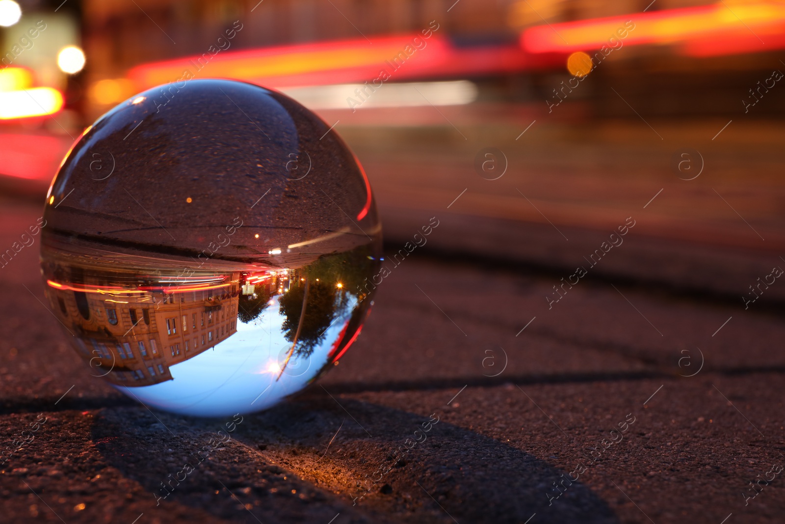 Photo of Beautiful city street, overturned reflection. Crystal ball on asphalt road at night. Space for text