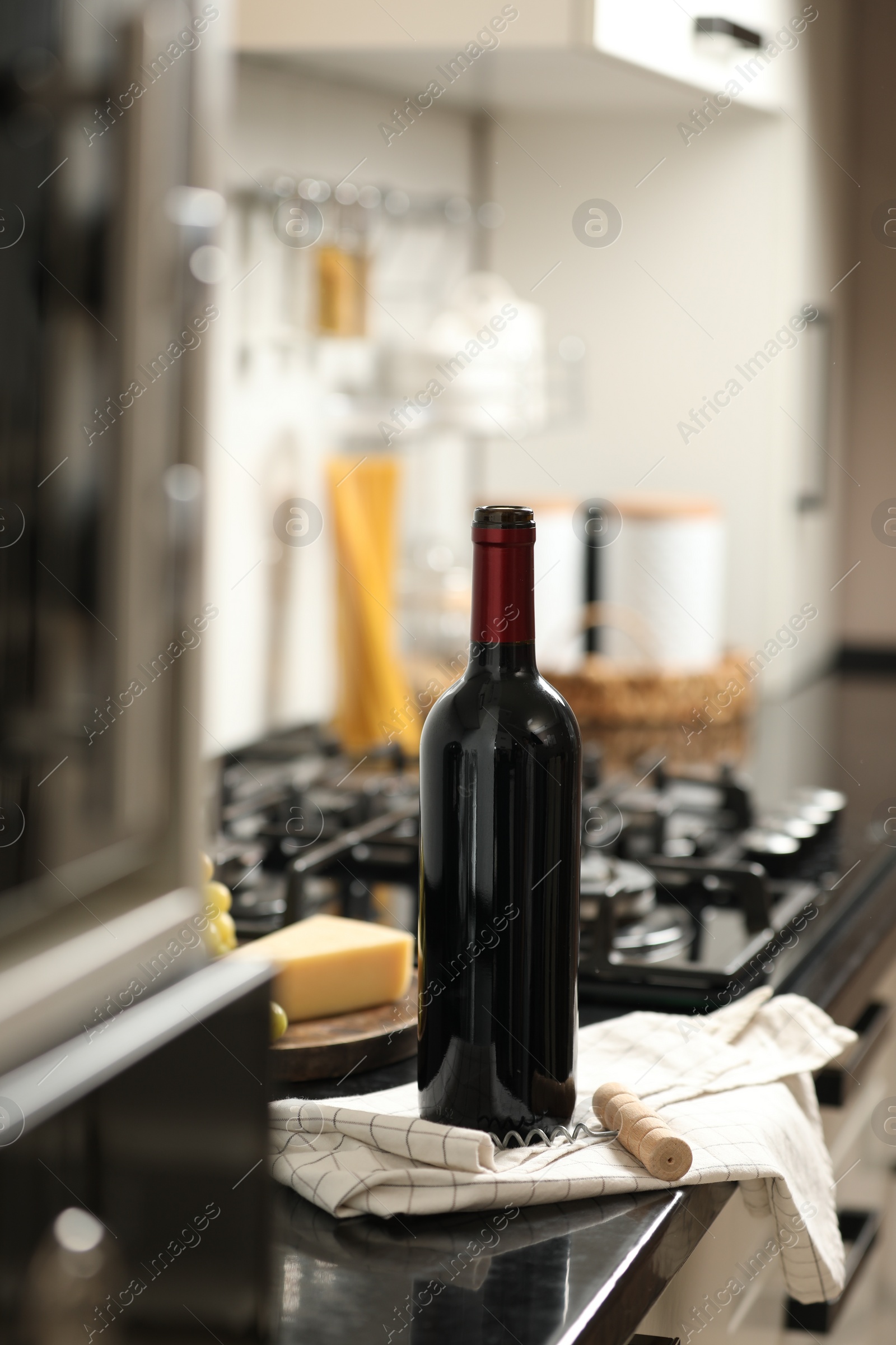 Photo of Corkscrew and open wine bottle on countertop in kitchen