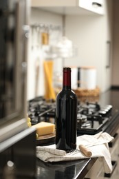 Photo of Corkscrew and open wine bottle on countertop in kitchen