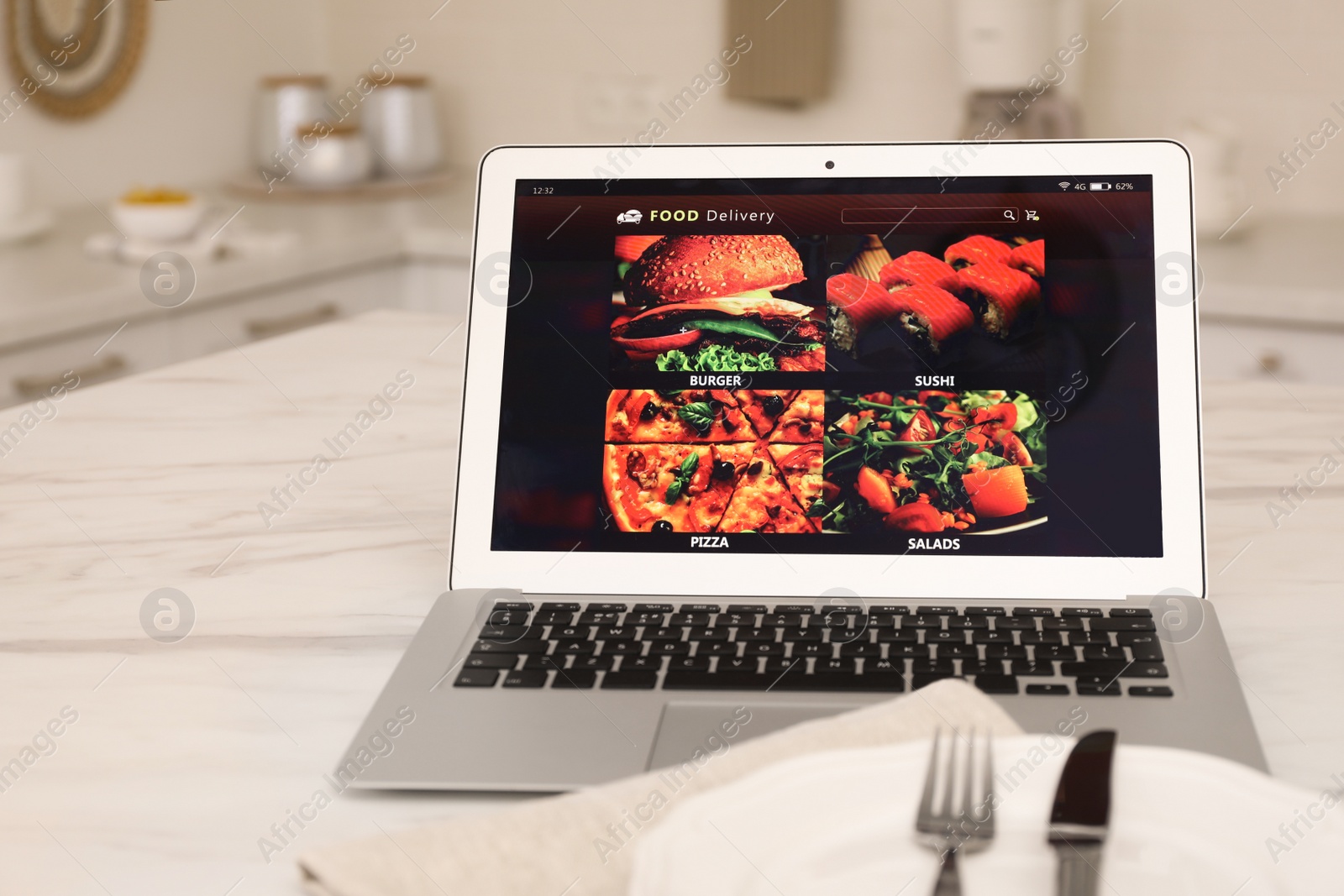 Photo of Modern laptop with open page for online food ordering on table in kitchen. Delivery service