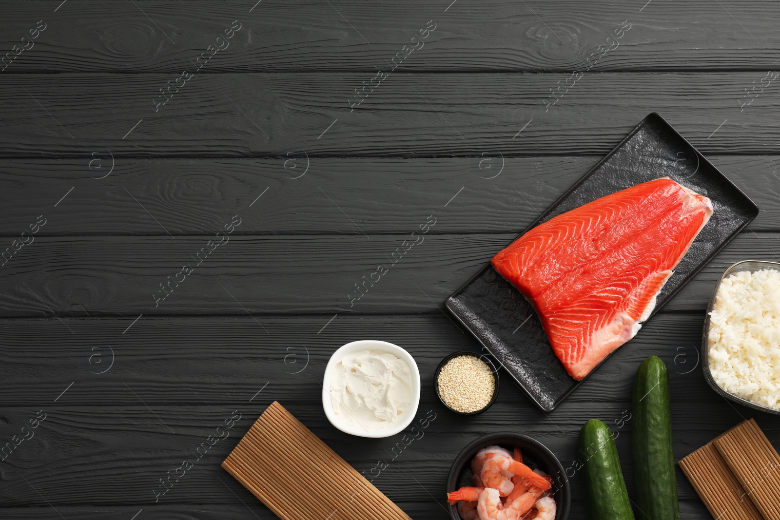 Photo of Making sushi rolls. Flat lay composition with ingredients on black wooden table. Space for text