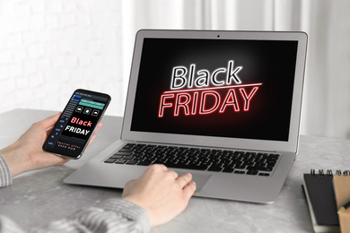 Black Friday. Woman shopping online using laptop and smartphone at table, closeup