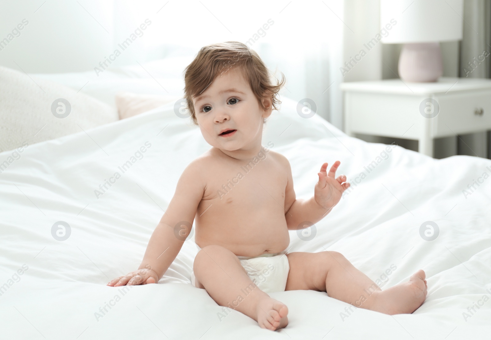 Photo of Cute little baby in diaper on bed