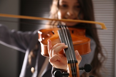 Photo of Preteen girl playing violin at music lesson, closeup