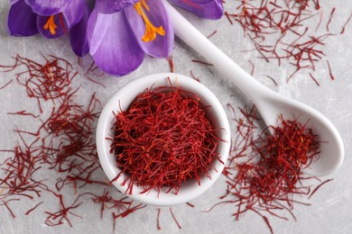 Photo of Dried saffron and crocus flowers on grey table, flat lay