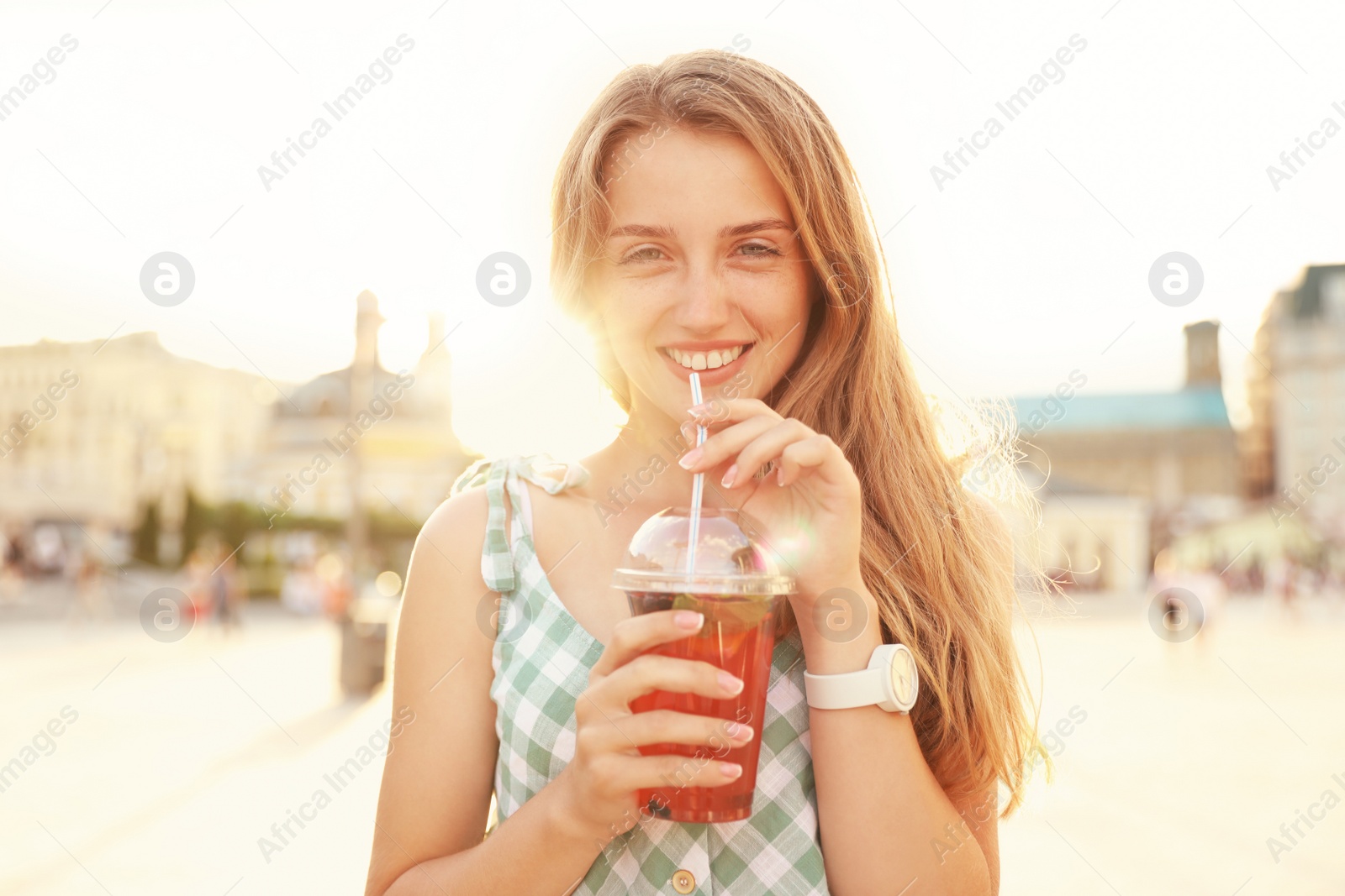 Photo of Young woman with refreshing drink on city street