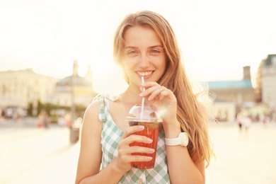 Young woman with refreshing drink on city street