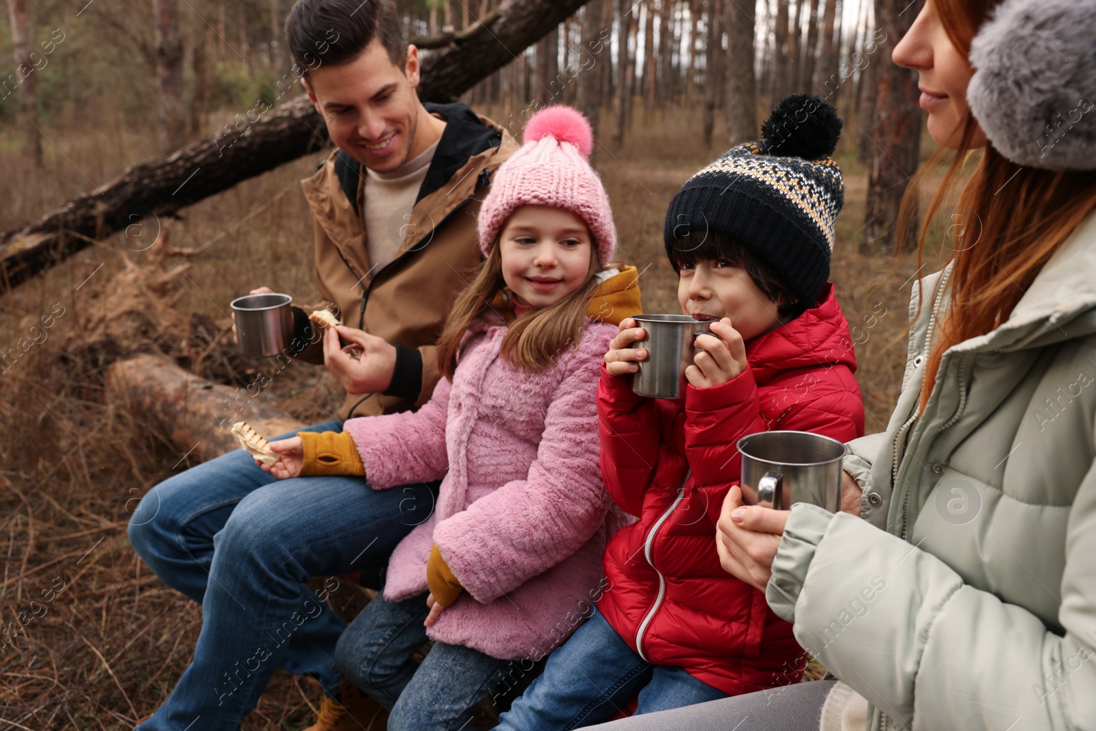 Photo of Happy family with hot drinks spending time together in forest
