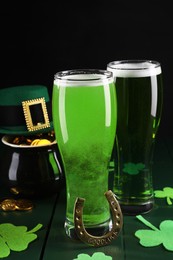 Photo of St. Patrick's day party. Green beer, leprechaun hat, pot of gold, horseshoe and decorative clover leaves on wooden table